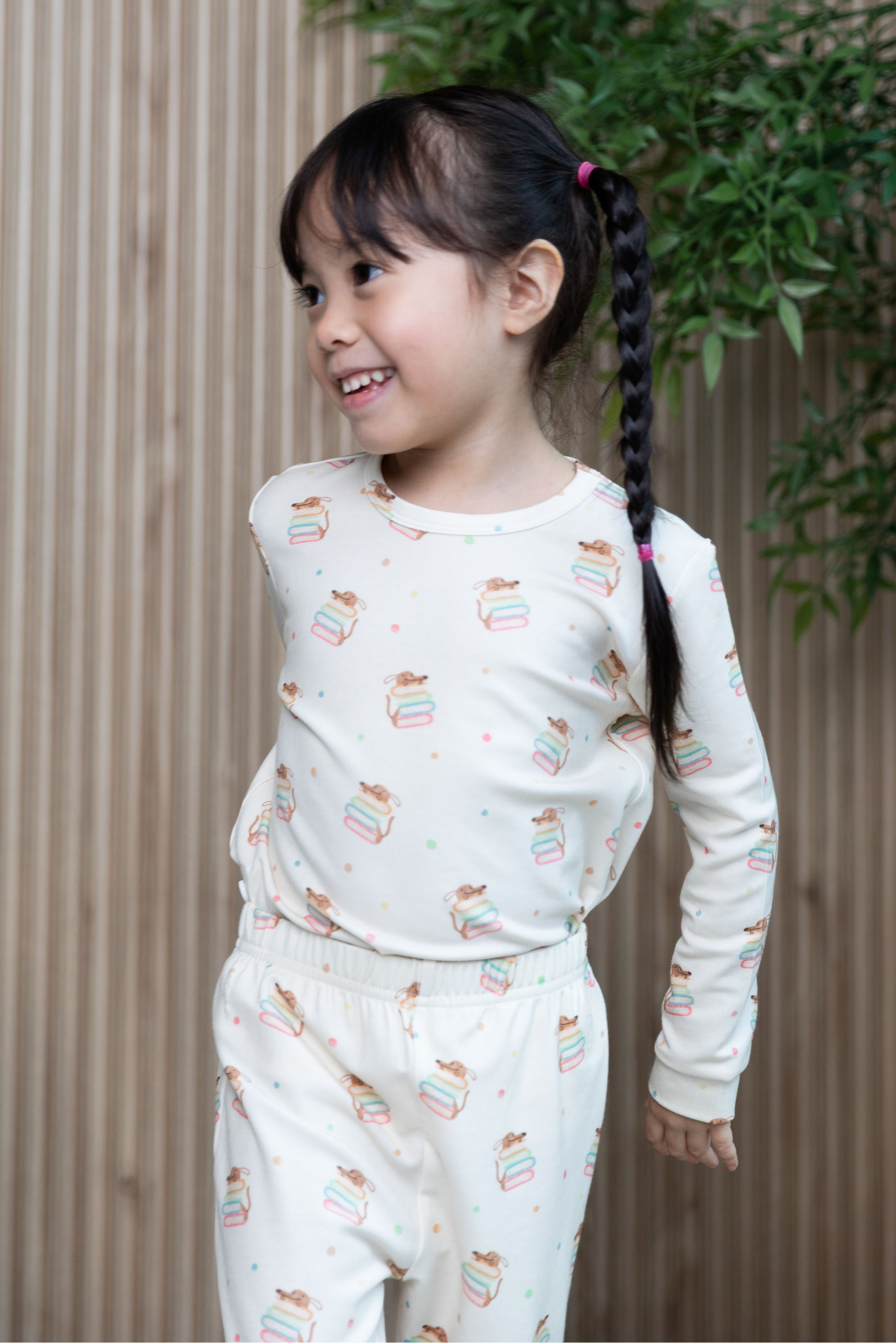 Smiling girl looking to the side wearing cream-coloured TENCEL™ pyjamas from Mama Pyjamain Storytime Pup print 