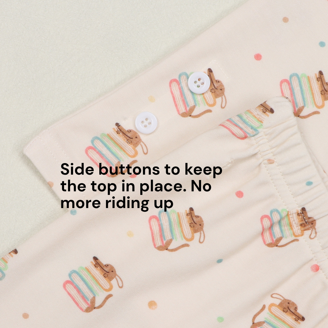 Beige pyjamas with pup hiding behind storybook print. Side buttons to keep the top in place. No more riding up